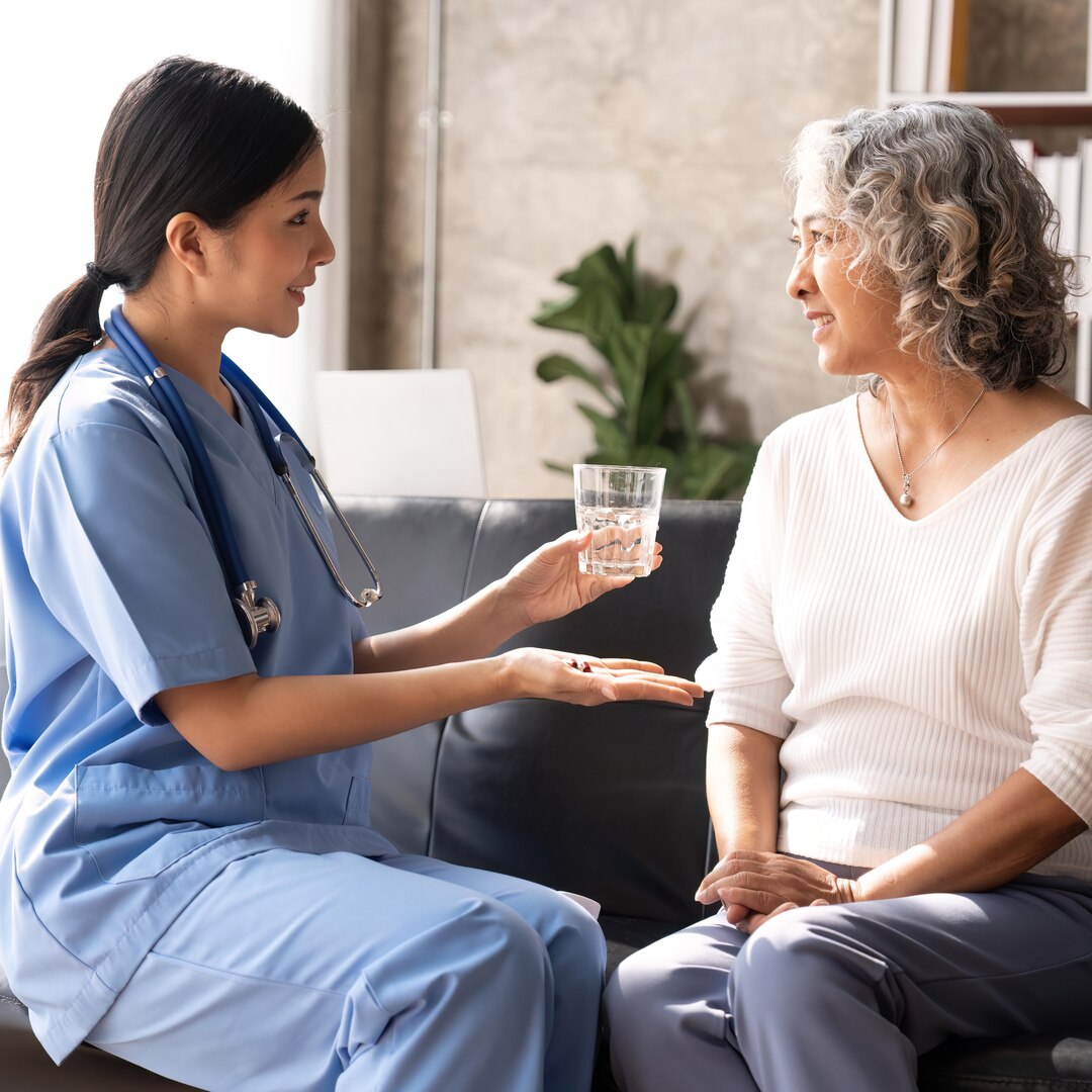 Healthcare worker or nurse caregiver giving pills, showing a prescription drug to senior woman